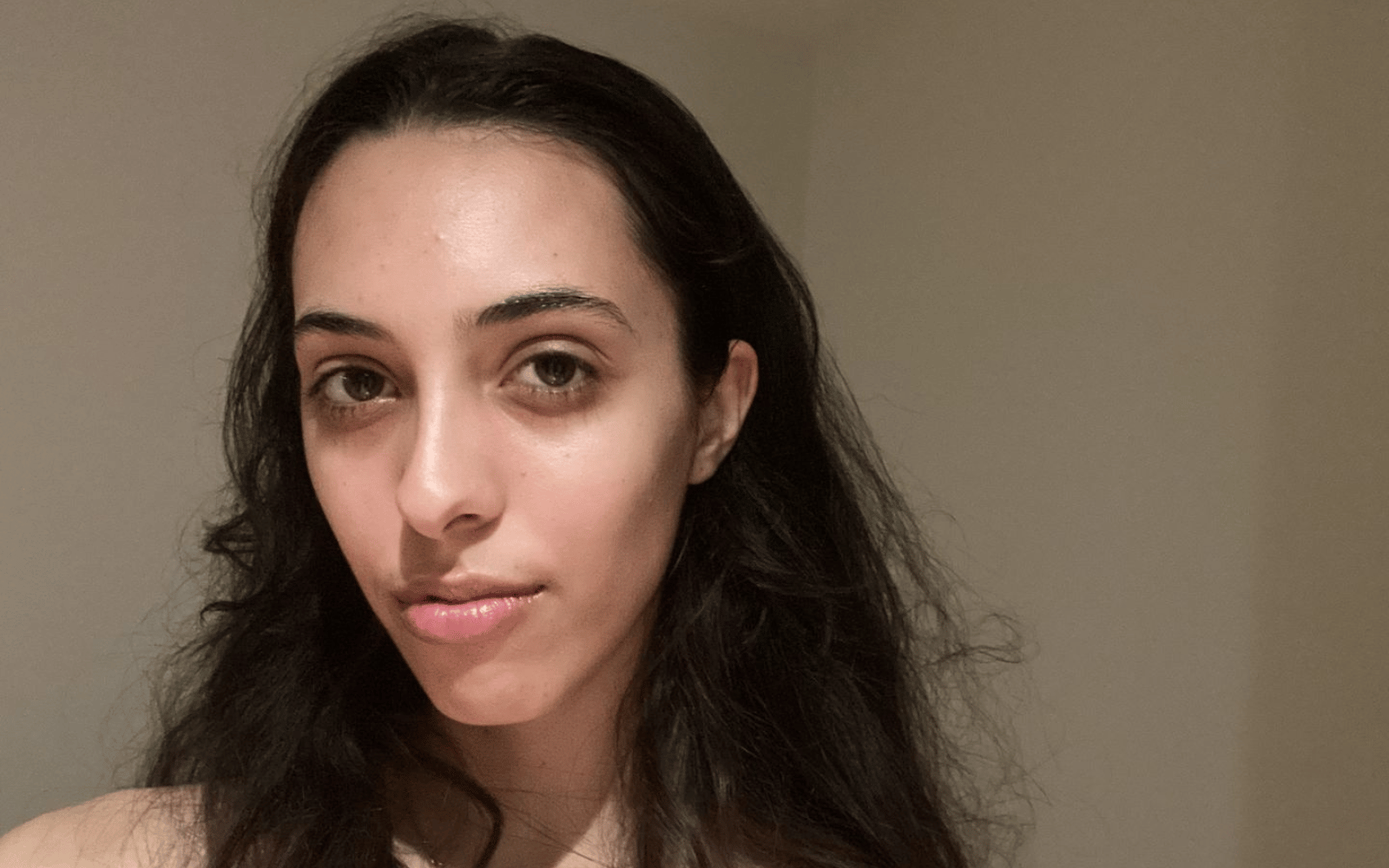 Témoignage cliente qui sourit et montre sa peau dans sa salle de bain